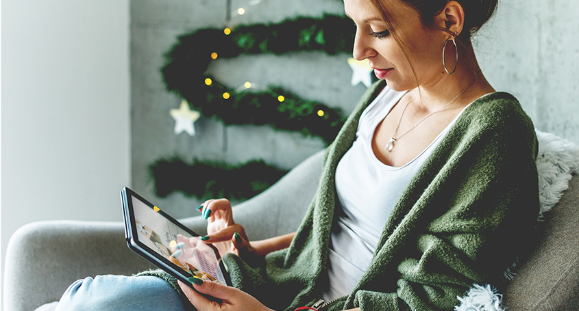 woman on the sofa during winter holidays reading emails on her tablet 
